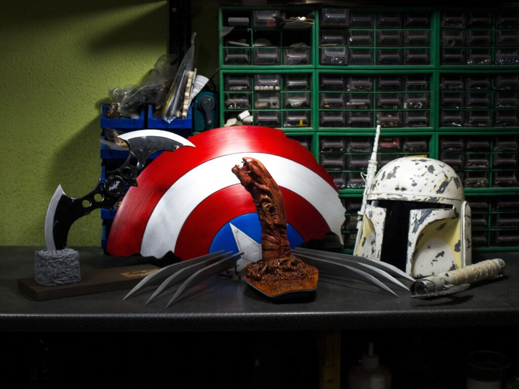 Props de cine: escudo del Capitán América, casco mandaloriano, garras de Lobezno, batarang y sable de luz.