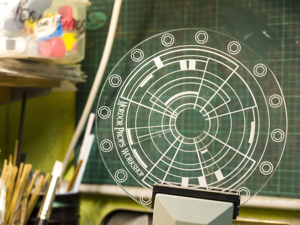 Plantilla de metacrilato grabada con el logotipo de Mordor Props Workshop.